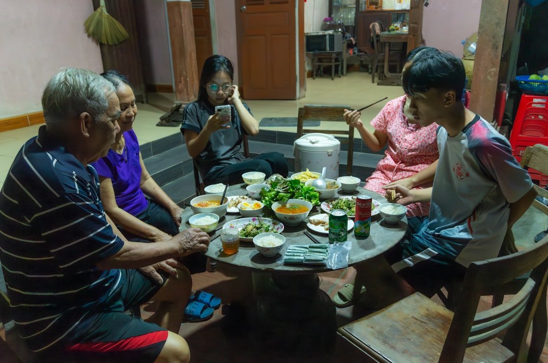 Solo traveler sharing meal with local family at traditional home dinner setting