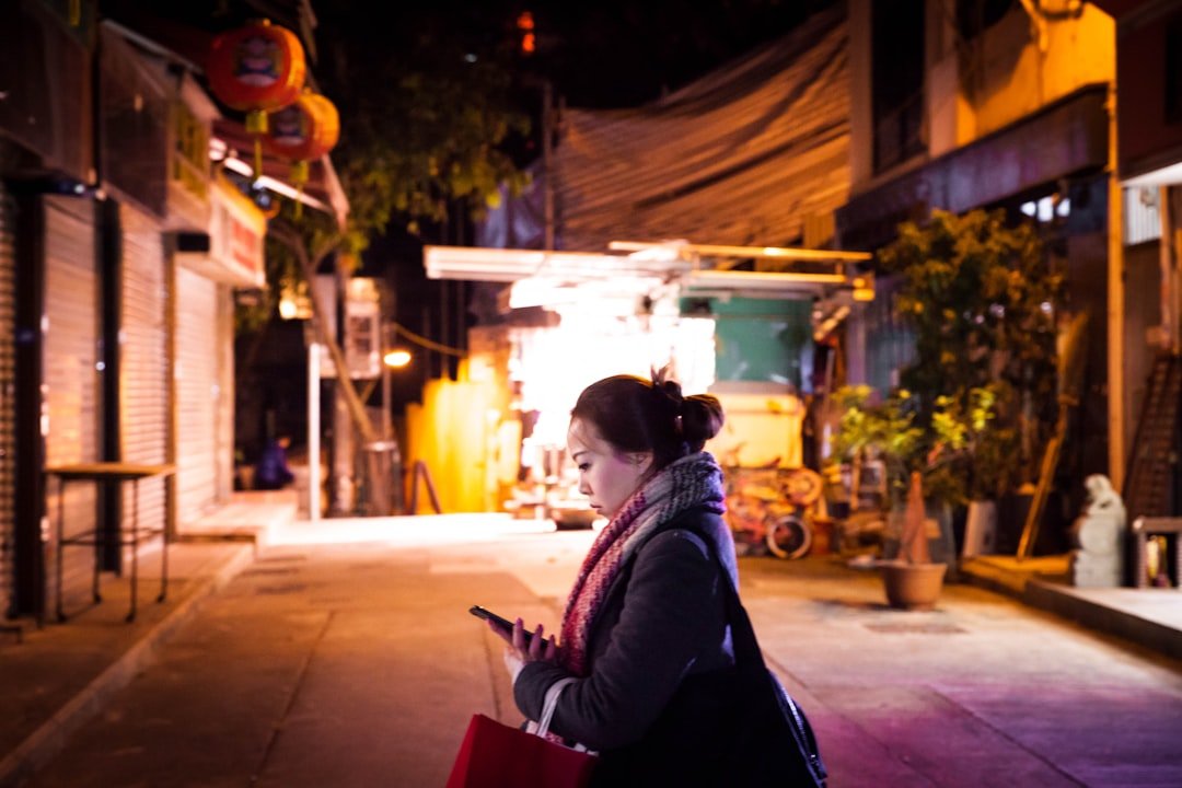 Woman traveler looking confidently at her phone map while walking through a safe, well-lit street at dusk